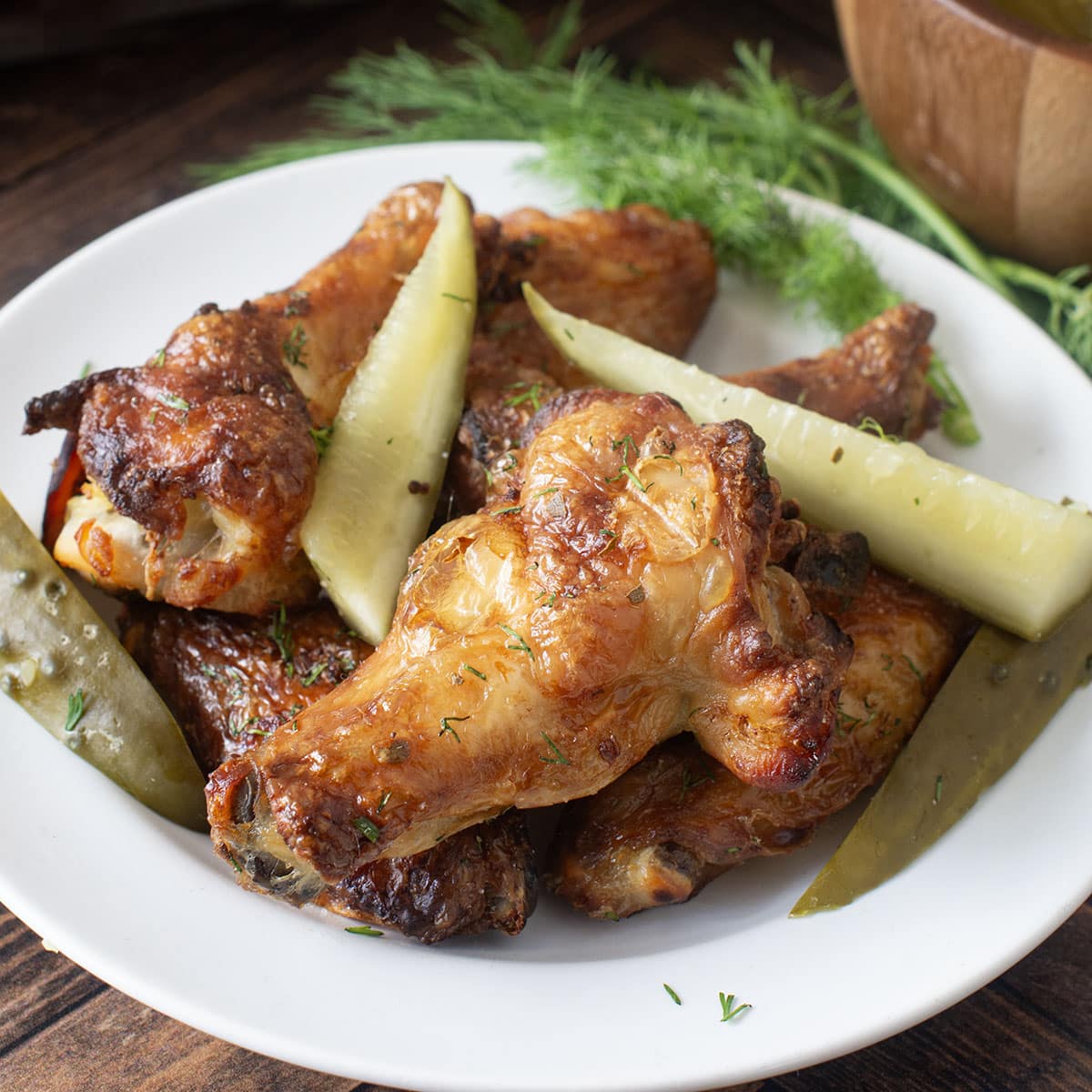 Plate of baked chicken wings and pickles.