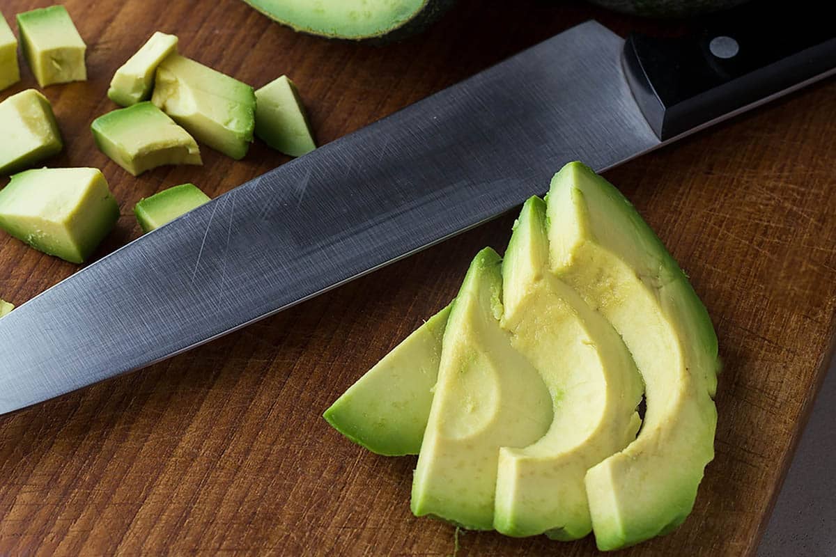 Avocado slices and cubes with knife.
