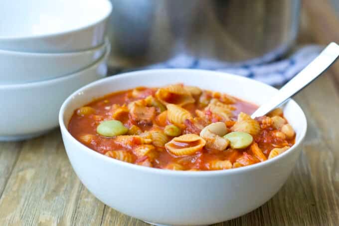 White bowl of pasta e fagioli soup with spoon.