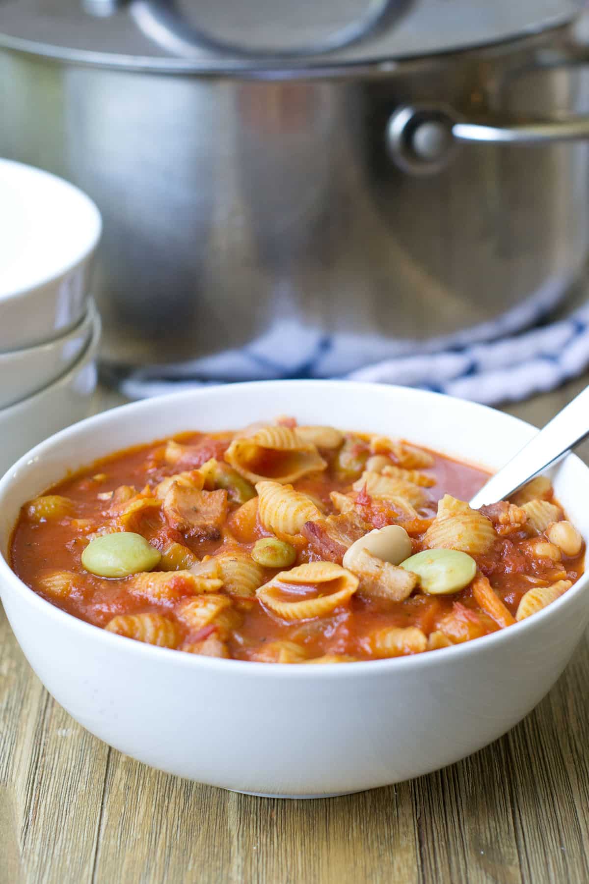 White bowl of pasta e fagioli soup with spoon.