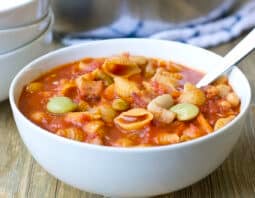 White bowl of pasta e fagioli soup with spoon.