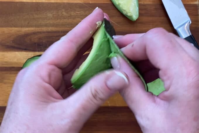 a wedge of avocado being peeled