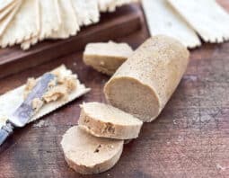Log of pumpkin spice butter with slices cut and crackers.