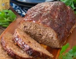 Meatloaf topped with bbq sauce with several slices cut.
