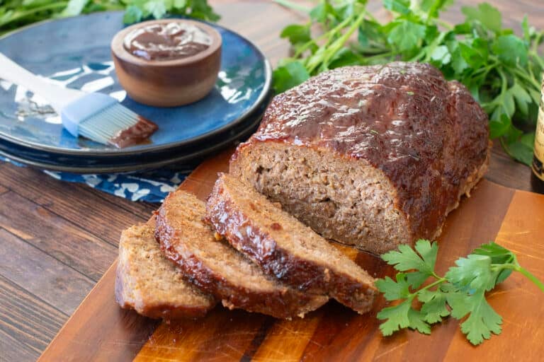 Meatloaf topped with bbq sauce with several slices cut.