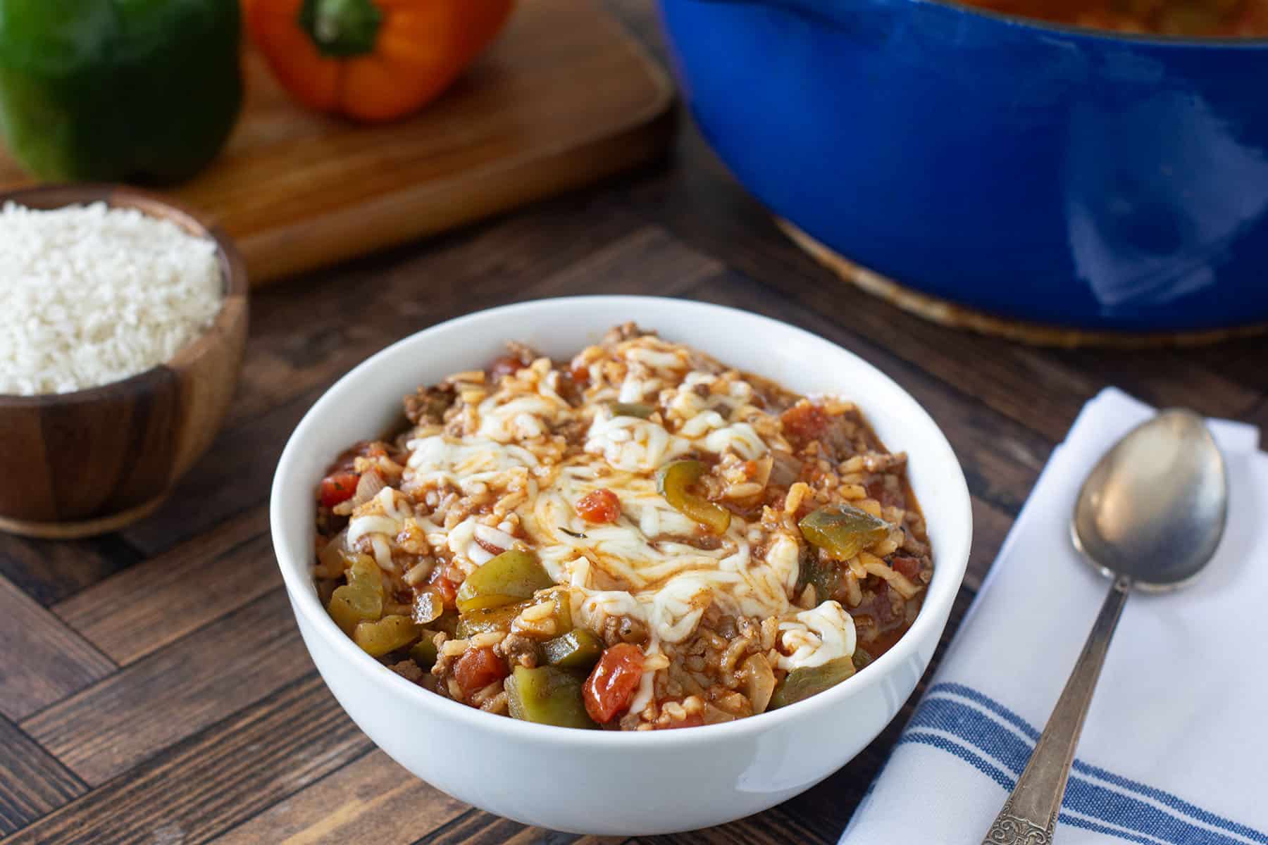 White bowl of stuffed pepper soup topped with melted mozzarella.